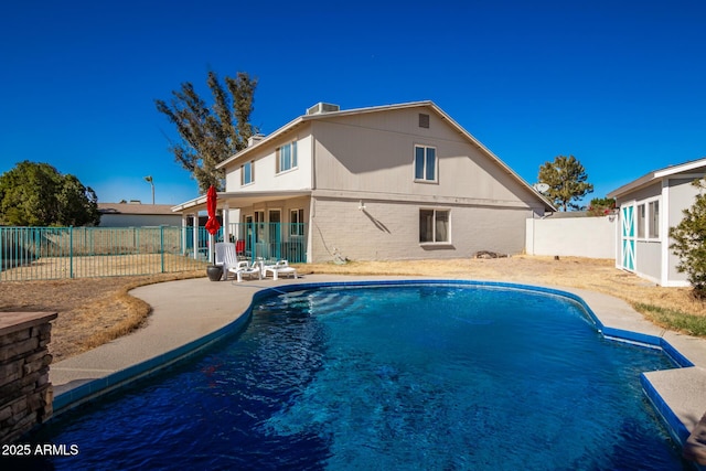 rear view of house featuring a fenced in pool and a patio area