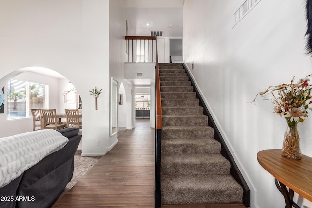 stairs with hardwood / wood-style flooring and a high ceiling