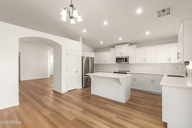 10212 E Caballero St, Mesa, AZ 85207 - kitchen with stainless steel appliances, a kitchen island, arched walkways, backsplash, and recessed lighting
