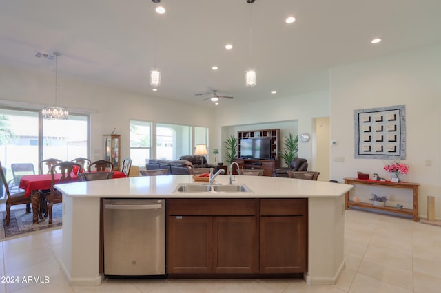 kitchen featuring ceiling fan with notable chandelier, a kitchen island with sink, stainless steel dishwasher, sink, and pendant lighting