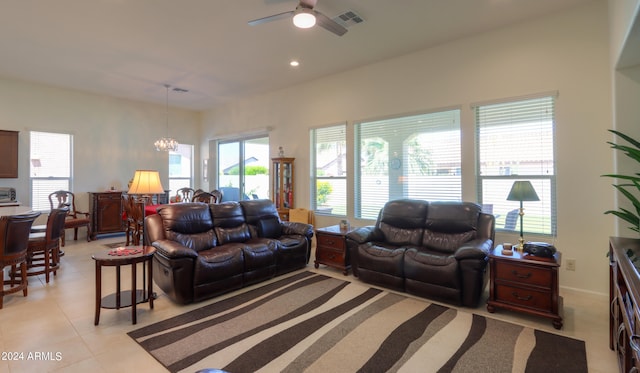 tiled living room with ceiling fan with notable chandelier