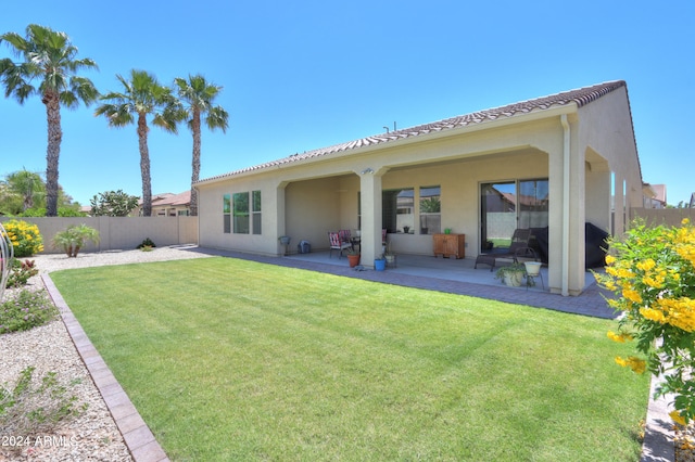 back of house with a patio and a lawn