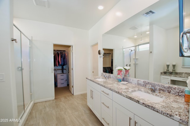 full bath featuring a stall shower, a walk in closet, and a sink