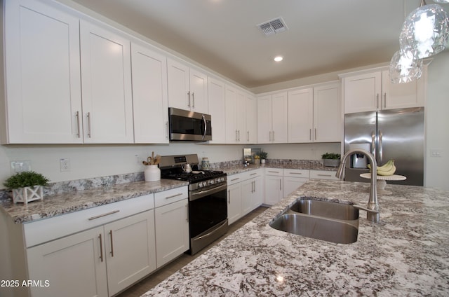 kitchen with visible vents, hanging light fixtures, stainless steel appliances, white cabinetry, and a sink