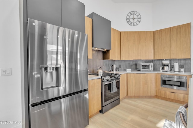 kitchen with tasteful backsplash, light wood-style flooring, modern cabinets, stainless steel appliances, and light countertops