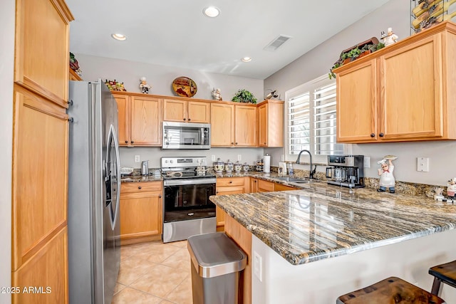 kitchen featuring sink, kitchen peninsula, stone counters, and stainless steel appliances