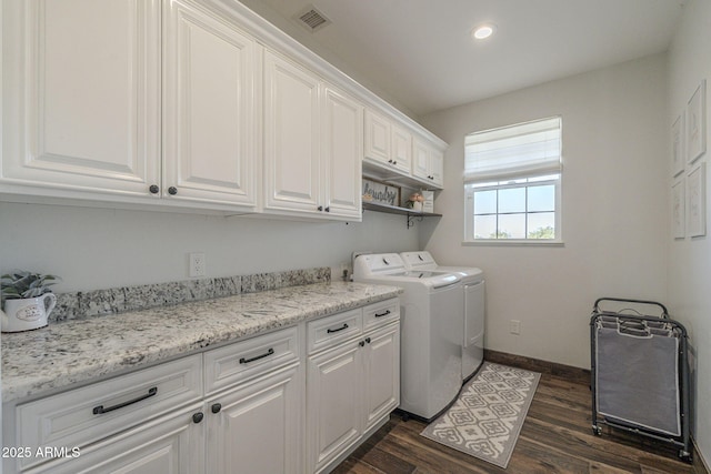 laundry room featuring washing machine and dryer, dark wood-type flooring, and cabinets