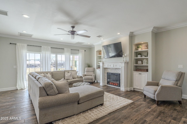 living room with ceiling fan, built in shelves, ornamental molding, and dark wood-type flooring