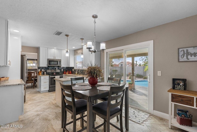 dining space featuring sink, a textured ceiling, and a notable chandelier