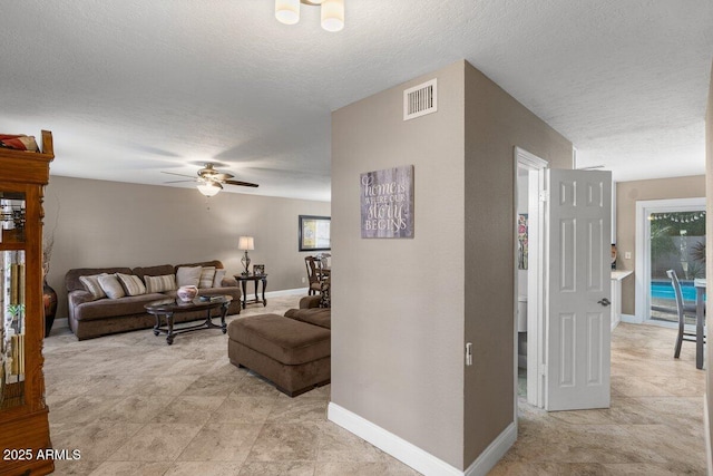 living room with ceiling fan and a textured ceiling