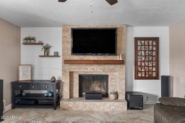 living room featuring ceiling fan, a fireplace, and a textured ceiling