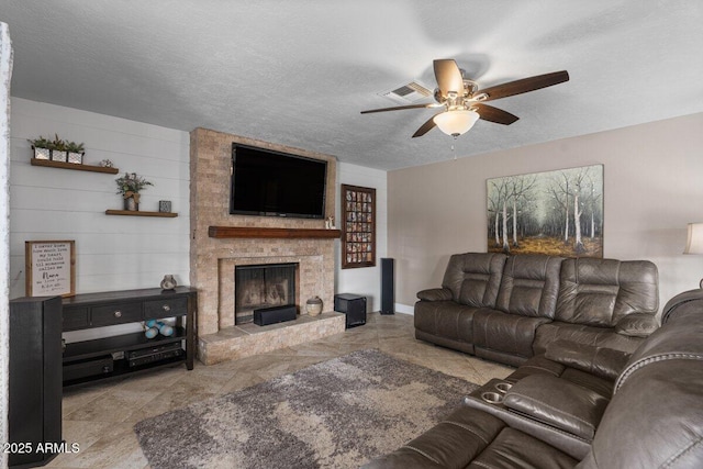 living room featuring ceiling fan, a fireplace, and a textured ceiling