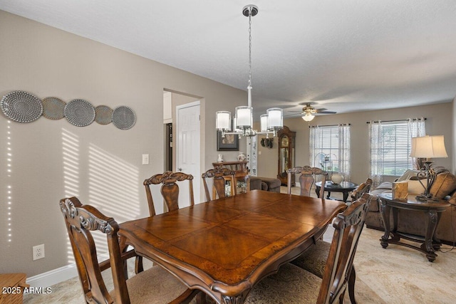 dining space with ceiling fan with notable chandelier