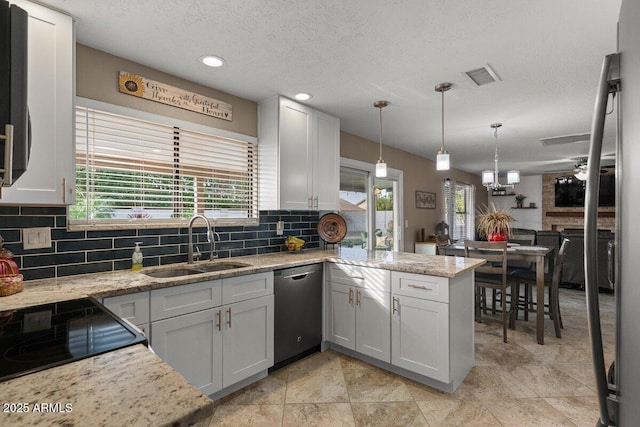 kitchen with sink, hanging light fixtures, stainless steel dishwasher, light stone counters, and kitchen peninsula