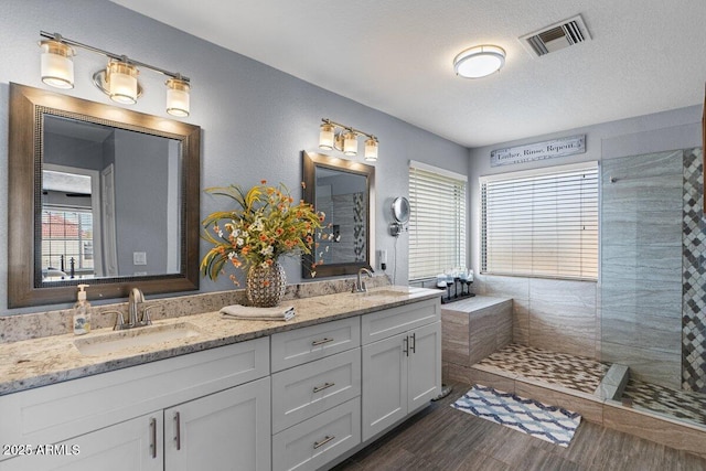 bathroom featuring vanity, a tile shower, wood-type flooring, and a textured ceiling