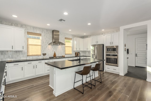 kitchen featuring white cabinets, stainless steel appliances, wall chimney exhaust hood, and dark hardwood / wood-style flooring