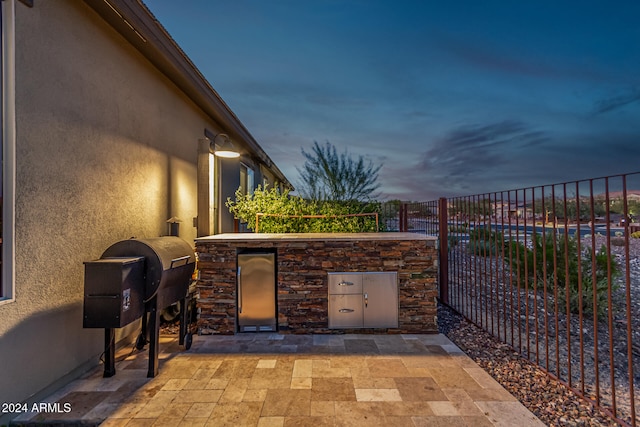 patio terrace at dusk featuring an outdoor kitchen and grilling area