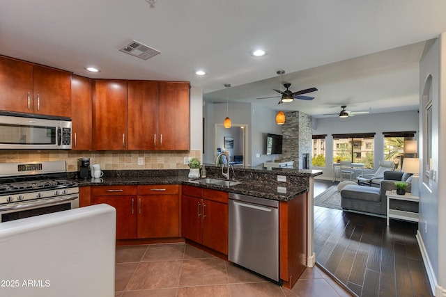 kitchen featuring tasteful backsplash, visible vents, appliances with stainless steel finishes, a peninsula, and a sink