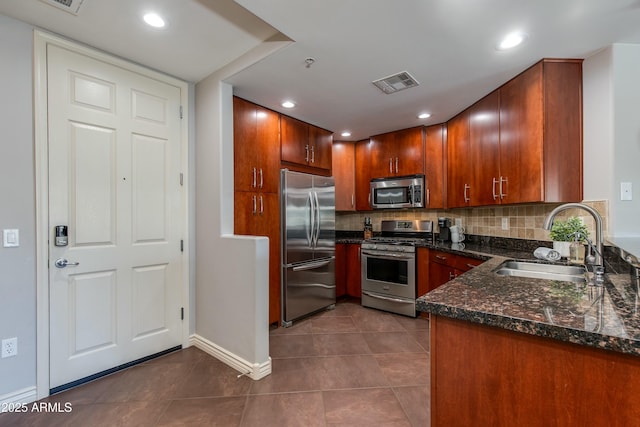 kitchen featuring tasteful backsplash, visible vents, dark tile patterned flooring, appliances with stainless steel finishes, and a sink