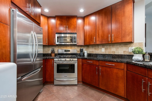 kitchen with tasteful backsplash, stainless steel appliances, dark stone countertops, and tile patterned floors