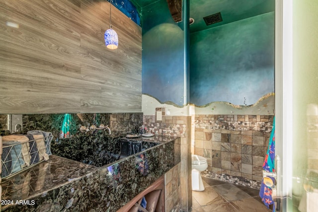 bathroom featuring tile walls and toilet