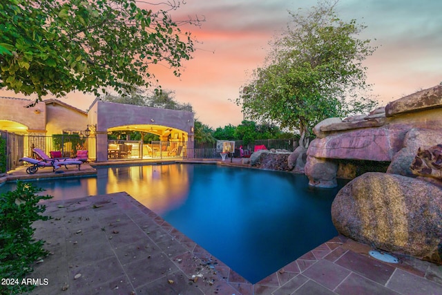 pool at dusk featuring a patio area