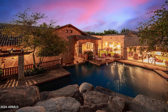 pool at dusk with a patio area