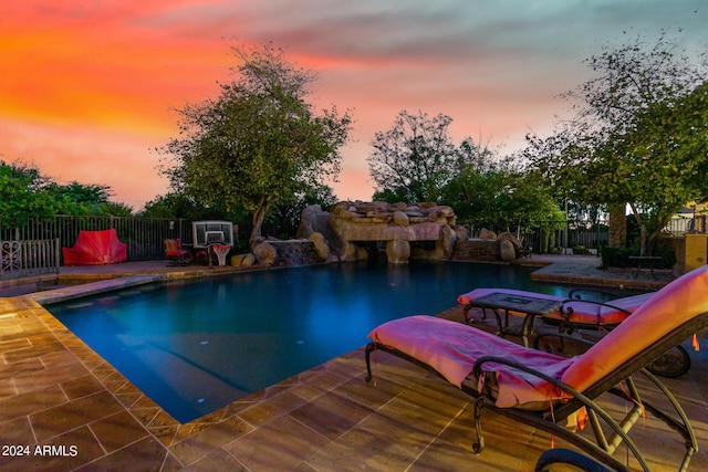 pool at dusk with a patio area