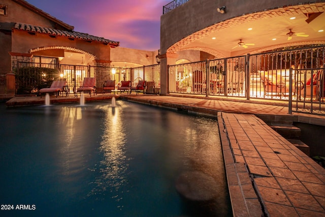 pool at dusk featuring a patio area and ceiling fan