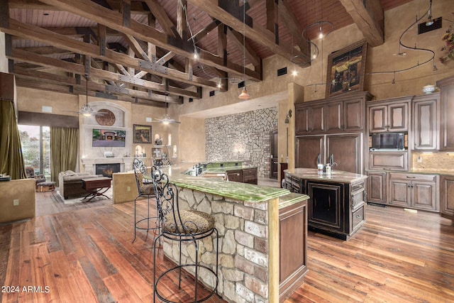 kitchen featuring a center island with sink, dark brown cabinetry, and high vaulted ceiling