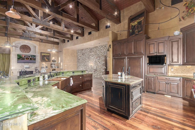 kitchen with beamed ceiling, light stone countertops, a spacious island, and wood ceiling