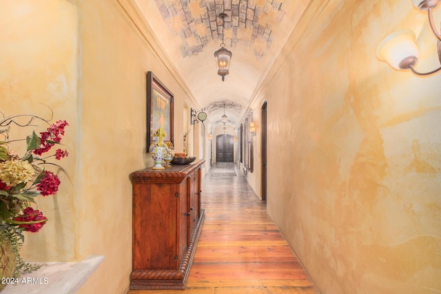 hall with ornamental molding, hardwood / wood-style flooring, lofted ceiling, and brick ceiling