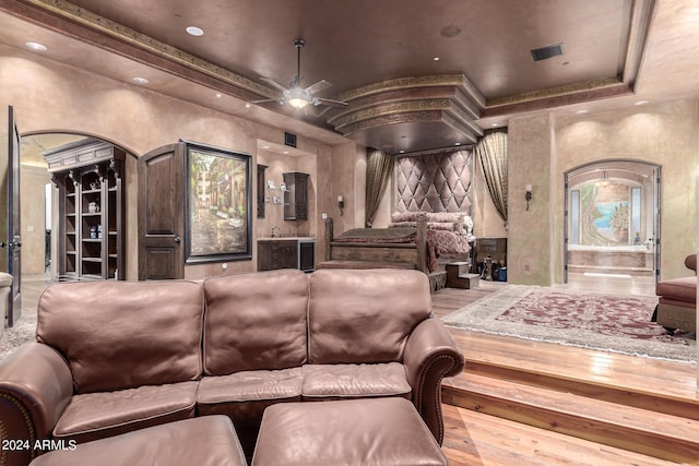 cinema with hardwood / wood-style flooring, ceiling fan, and a tray ceiling