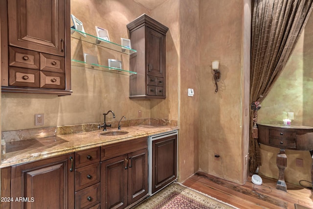 kitchen with dark brown cabinets, light stone countertops, and sink