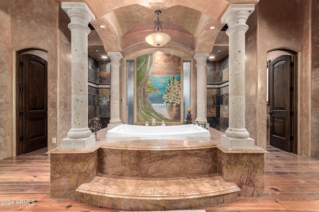 bathroom featuring hardwood / wood-style flooring, a bathtub, and ornate columns