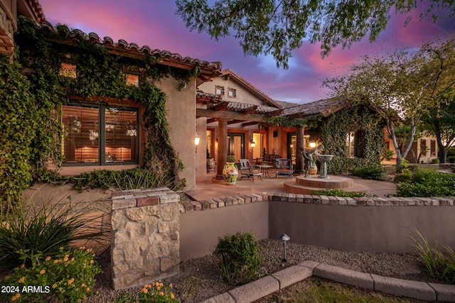 back house at dusk featuring a patio