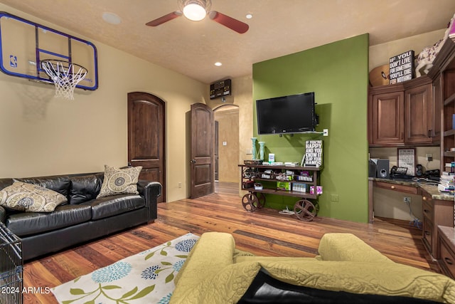 living room featuring ceiling fan, built in desk, and light wood-type flooring