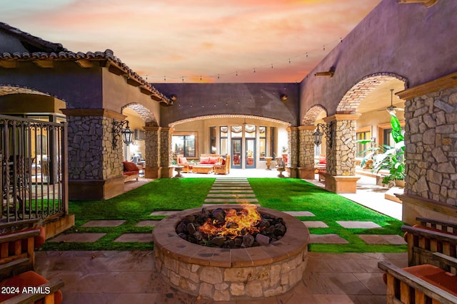 exterior space with french doors, an outdoor living space with a fire pit, and a patio