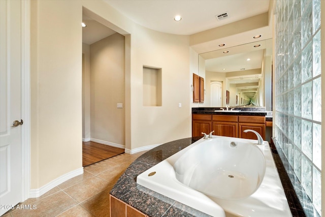 bathroom featuring tile patterned flooring, vanity, and tiled tub