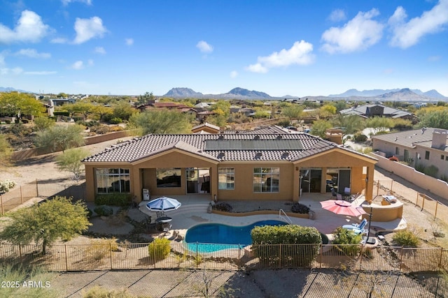 back of house with a patio area, a mountain view, a swimming pool with hot tub, and solar panels