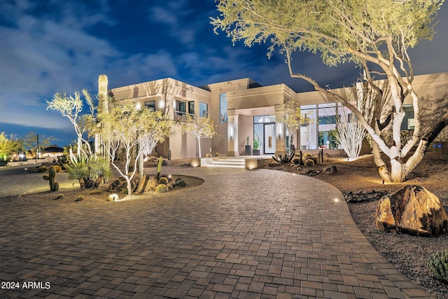 view of front of house featuring stucco siding and curved driveway