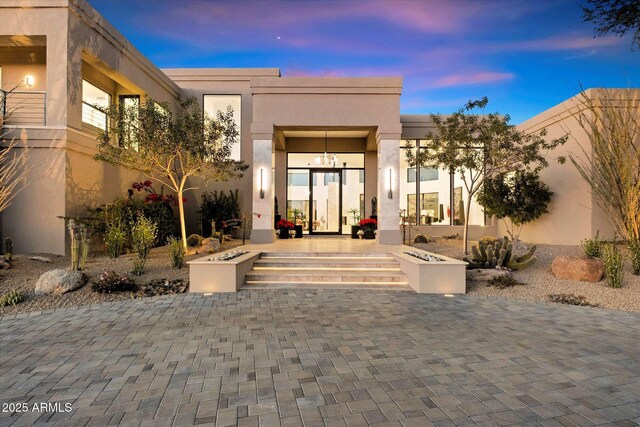 exterior entry at dusk featuring a patio area