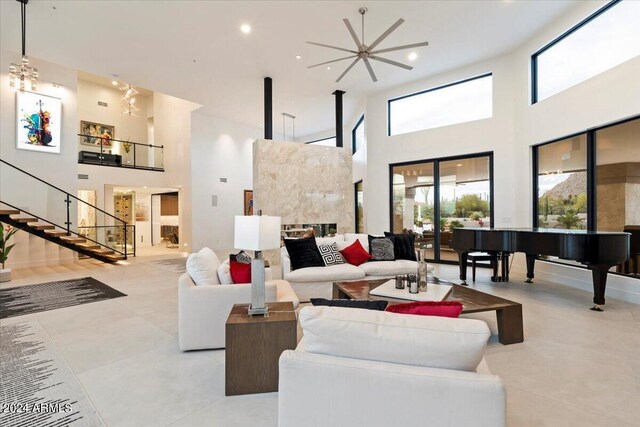 living room featuring a healthy amount of sunlight, a high ceiling, a fireplace, and ceiling fan