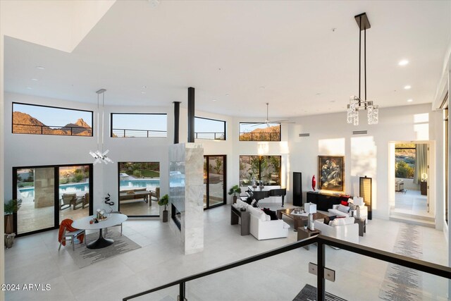 living room with a towering ceiling, ceiling fan, and a premium fireplace