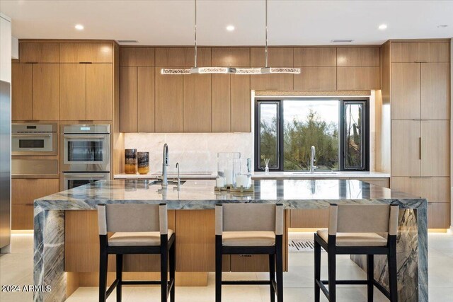 kitchen with a breakfast bar area, sink, stainless steel double oven, decorative light fixtures, and a spacious island