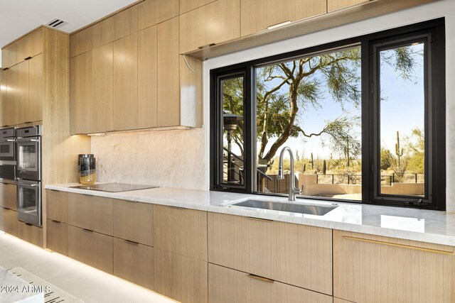 kitchen with pendant lighting, light tile patterned flooring, sink, black electric cooktop, and dark stone countertops