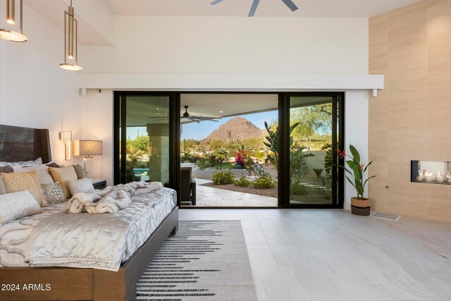 bedroom featuring access to outside, ceiling fan, and a tile fireplace