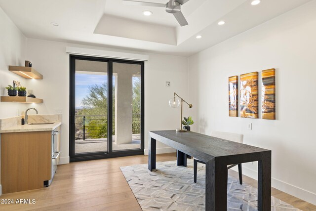 home office with a tray ceiling and hardwood / wood-style flooring