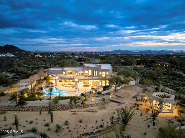 pool at dusk with a patio, outdoor lounge area, and a bar