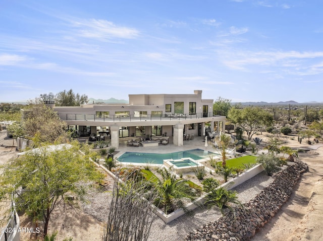 back of house with a pool with hot tub, a balcony, a mountain view, and a patio area